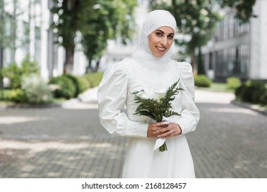 joyful muslim bride with diamond ring on finger holding wedding bouquet
