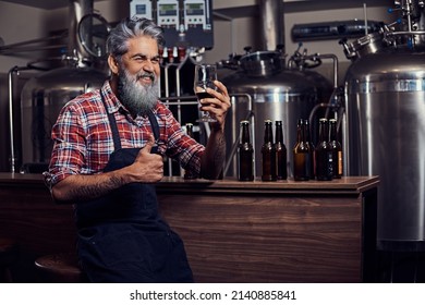 Joyful old brewer showing thumbs up tasting his beer - Powered by Shutterstock