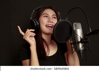 Joyful Optimistic Glad Young Female Singer With Microphone And Headphone For Audio Recording In The Private Studio. Music, Show Business, People Singer And Voice Concept. Bangkok Thailand Asia