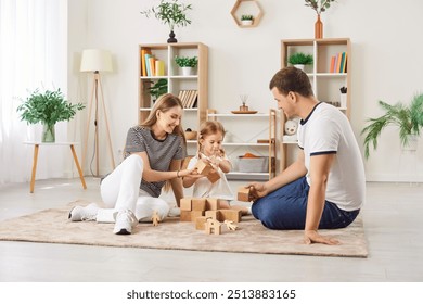 Joyful parents playing wooden blocks game with their daughter on floor in living room, helping preschool child to build toy tower. Family activities together at home. Having fun, learning creativity. - Powered by Shutterstock