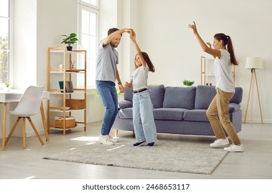 Joyful people having fun at home. Happy vibrant family dancing to lively music together. Young energetic mother, father and child having party and dancing in modern spacious cozy living room interior - Powered by Shutterstock