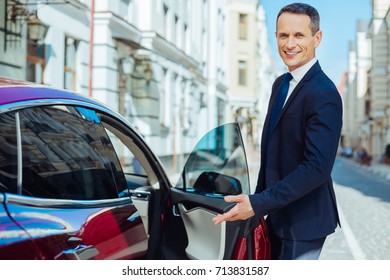 Joyful Polite Man Pointing To The Car Seat