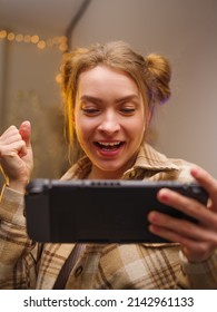 Joyful pretty girl with a portable game console. Online games with friends, win prizes. Fun entertainment. Teenagers play adventure games online. Youth culture, game strategy, cybersport.