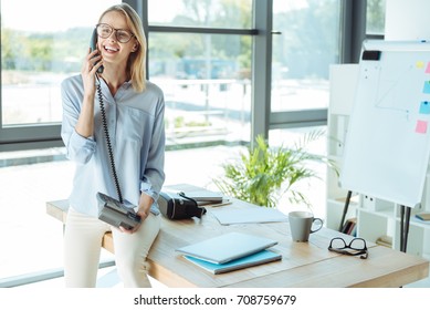 Joyful Pretty Woman Talking On The Landline Phone In Office