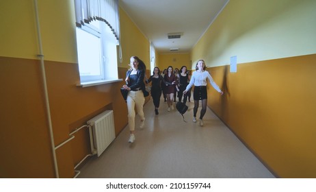 Joyful schoolgirls run after the end of the lessons in the school corridor.