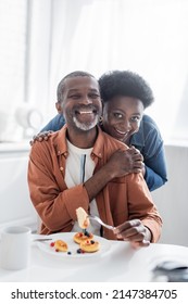 joyful and senior african american couple looking at camera during breakfast