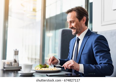 Joyful senior businessman enjoying meal in restaurant