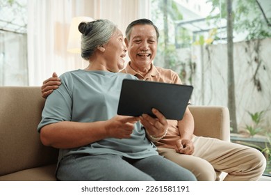 Joyful senior couple watching funny videos on tablet computer - Powered by Shutterstock