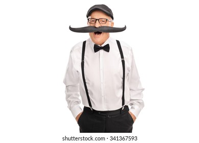 Joyful Senior Gentleman With A Bow-tie And Suspenders Posing With A Big Fake Moustache Isolated On White Background