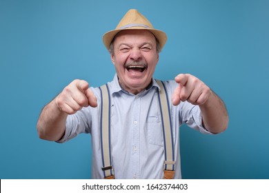 Joyful Senior Hispanic Man Pointing At You Laughing. Funny Joke Or Prank Concept.