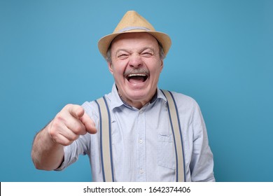 Joyful Senior Hispanic Man Pointing At You Laughing. Funny Joke Or Prank Concept.