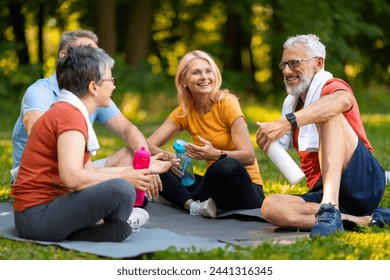 Joyful senior yoga enthusiasts enjoying friendly chat while sitting on mats outdoors, happy elderly people holding water bottles, older men and women relaxing after refreshing session in summer park - Powered by Shutterstock