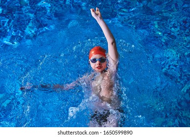 Joyful smiling boy swimmer in a cap and Goggles learns professional swimming in the swimming pool in gym close up - Powered by Shutterstock