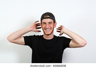 Joyful And Smiling Happy Young Adult Male In Dark T-Shirt And Baseball Hat Worn Backwards