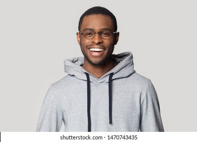 Joyful Smiling Millennial African American Male Student In Stylish Hoodie Looking At Camera Head Shot Close Up Portrait. Laughing Overjoyed Happy Black Young Man Isolated On Grey Studio Background.