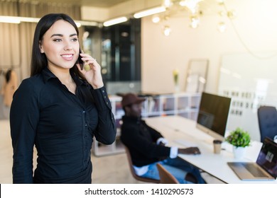 joyful smiling young businesswoman having negotiations by phone in office