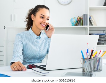 joyful smiling young businesswoman having negotiations by phone in office