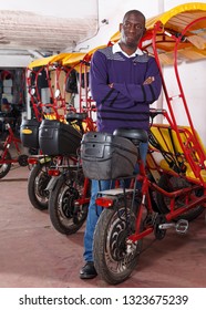 Joyful successful African American driver of pedicab offering touristic tour