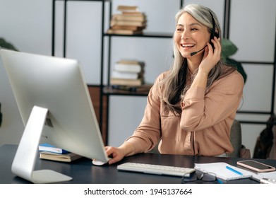 Joyful Successful Beautiful Mature Asian Business Woman Call Center Manager Working In Office, Communicating With Business Team Via Virtual Conference, Video Call, Using Headset, Smiling Friendly