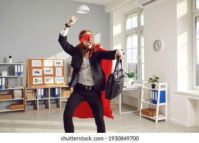 Joyful Superhero Businessperson Or Corporate Employee Dancing And Fooling Around. Funny Goofy Young Office Worker In Super Hero Cape And Mask Having Fun At End Of Work Day Happy It's Time To Go Home