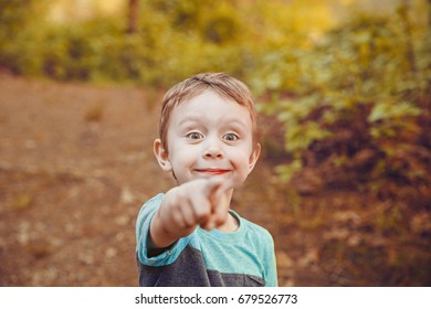 Joyful and surprised boy pointing at something. Curious kid smiles happily after seeing something amazing. Close up