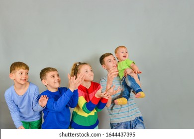 Joyful And Surprised Children Catch A Falling Object From Above. The Rivalry Between The Children Who First Catch