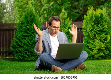 Joyful Surprised Middle Aged Businessman Sits On Grass Works Outdoors, Looks With Surprise At Laptop Screen, Man Happy With Stock Growth And Higher Earnings Profit, Winner, Success Concept, Copy Space