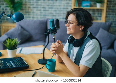 Joyful teen is speaking in microphone in studio audio recording podcast alone using modern equipment. Youth, communication and professional blogging concept. - Powered by Shutterstock