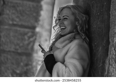 Joyful tourist enjoying a day in an ancient european city, taking a break to check her smartphone in a charming alleyway - Powered by Shutterstock