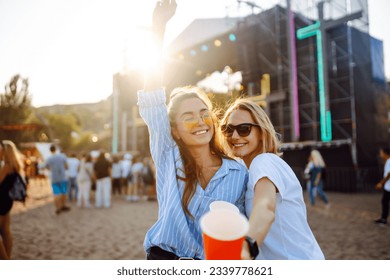 Joyful two young girlfriends have fun with beer at the beach party. Happy two women enjoy the weekend at the music festival. The concept of friendship, holiday, weekend. - Powered by Shutterstock