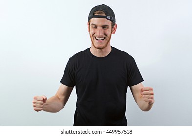 Joyful, Very Happy Smiling Young Adult Male In Dark T-Shirt And Baseball Hat Worn Backwards