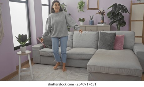 A joyful woman dances casually in a modern living room, reflecting a cozy, relaxed home atmosphere.