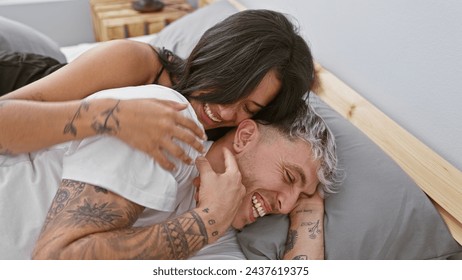 A joyful woman embraces a laughing man as they relax together in a cozy bedroom setting, portraying a sense of love and intimacy. - Powered by Shutterstock