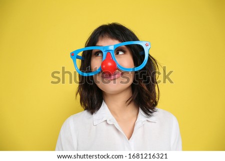 Joyful woman with funny glasses on yellow background. April fool's day