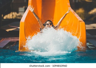 joyful woman going down on the rubber ring by the orange slide make the water splashing in the aqua park. Summer Vacation. Weekend on resort