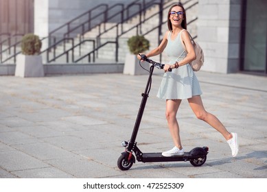 Joyful Woman Riding A Kick Scooter