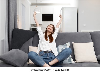 joyful woman sitting comfortably on the couch relaxing at home - Shutterstock ID 1923329855