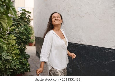 A joyful woman walks through a vibrant alleyway, embracing the moment with a smile. The setting accentuates her carefree spirit. - Powered by Shutterstock