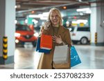 A joyful woman wearing a brown coat talks excitedly on her phone while holding shopping bags in an underground parking lot. The scene conveys a sense of satisfaction and success.