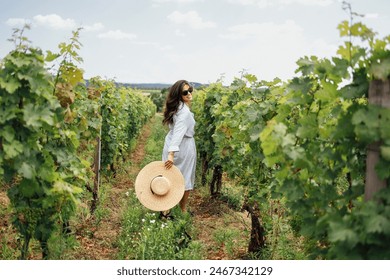 Joyful woman, wearing a hat, in a vineyard in the sun. Holiday and travel concept. Back view - Powered by Shutterstock