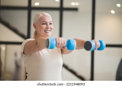 Joyful woman working out with hand weights - Powered by Shutterstock