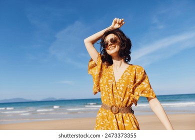 Joyful woman in a yellow dress enjoying the freedom and beauty of the beach on a sunny day - Powered by Shutterstock