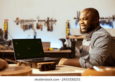 Joyful woodworker and BIPOC coworker using CAD software on green screen laptop to design wooden objects. Cheerful carpenters using program on mockup notebook to plan furniture assembling in joinery - Powered by Shutterstock