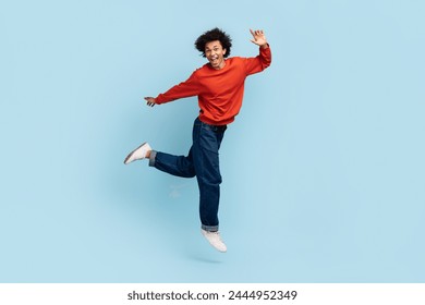 Joyful young african american man with curly hair jumping in mid-air expressing elation - Powered by Shutterstock