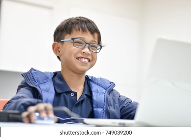 The joyful young Asian boy enjoys his computer class.