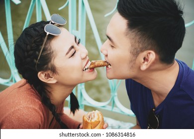 Joyful young Asian couple sharing the last piece of chicken