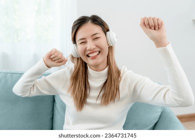 Joyful young Asian women in wireless headphones sitting and enjoy music, having fun, listening to music, raising his arm, dancing to favorite song, enjoying cool soundtrack, happy life, recreation - Shutterstock ID 2364731745