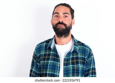 Joyful young bearded hispanic man wearing plaid shirt over white background looking to the camera, thinking about something. Both arms down, neutral facial expression. - Powered by Shutterstock