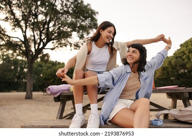 Joyful young caucasian girls have cool time on picnic in fresh air. Brunettes wear T-shirts, shorts and shirts. Spring season concept