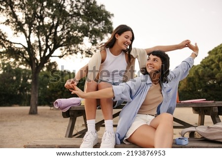 Joyful young caucasian girls have cool time on picnic in fresh air. Brunettes wear T-shirts, shorts and shirts. Spring season concept
